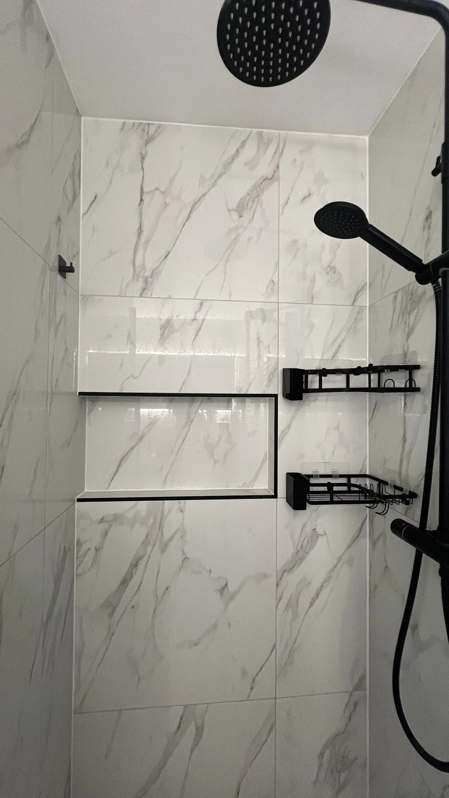 Walk-in shower with recessed niche edged in black trim and a matt black rainfall shower