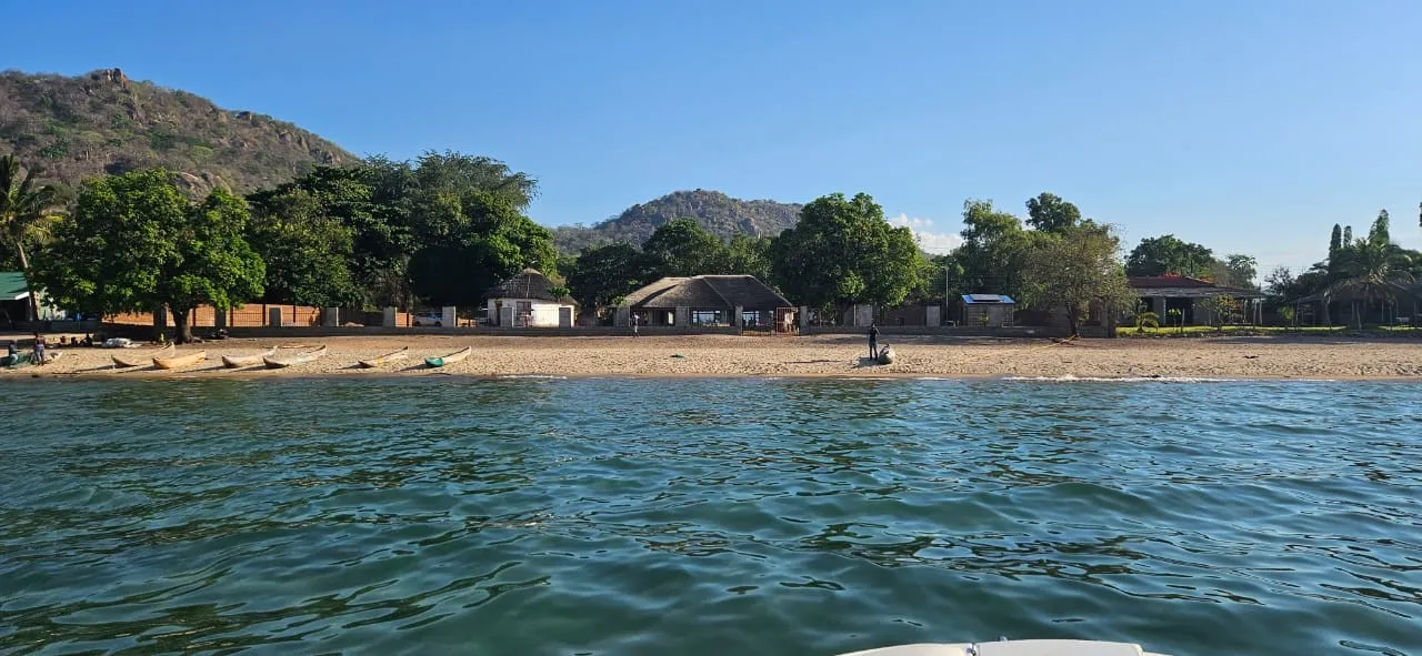 The lakeshore setting: beach, fishing canoes and hills behind